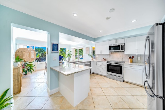 kitchen with tasteful backsplash, appliances with stainless steel finishes, sink, white cabinets, and kitchen peninsula