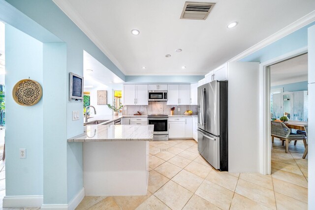 kitchen with decorative backsplash, kitchen peninsula, white cabinets, stainless steel appliances, and sink