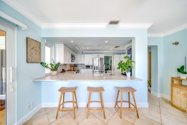 kitchen with crown molding, stainless steel appliances, white cabinets, tasteful backsplash, and kitchen peninsula