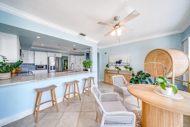 tiled dining room featuring sink, crown molding, and ceiling fan