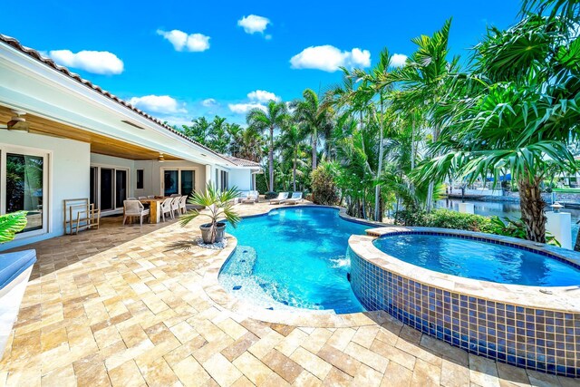 view of swimming pool with ceiling fan, a patio, an in ground hot tub, and pool water feature