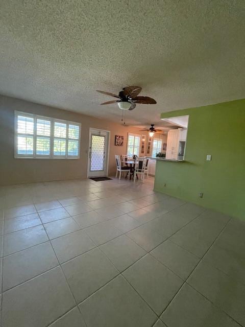 spare room with ceiling fan, a textured ceiling, and light tile patterned floors