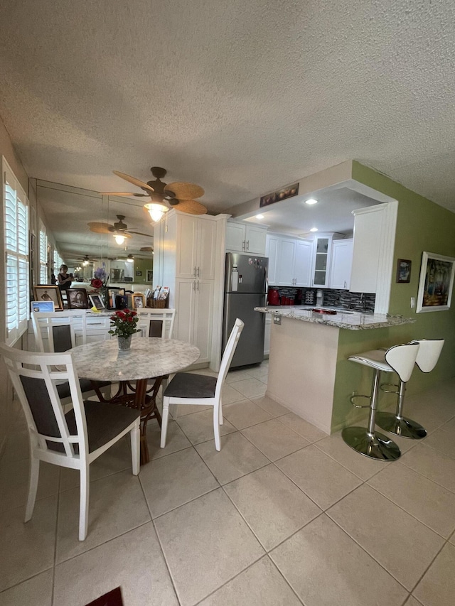 tiled dining room with ceiling fan and a textured ceiling