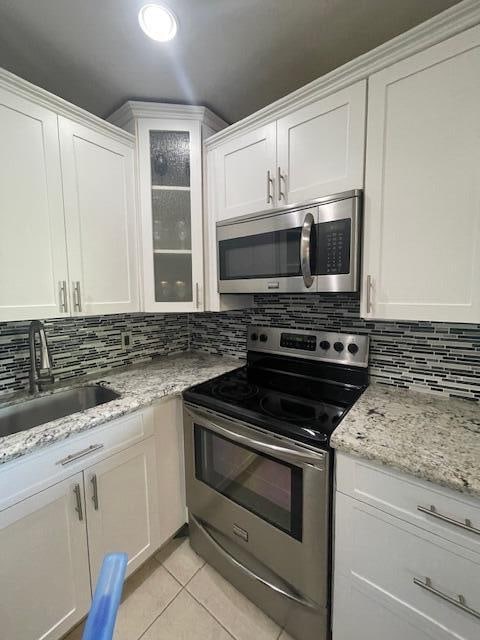 kitchen with decorative backsplash, white cabinetry, appliances with stainless steel finishes, and sink