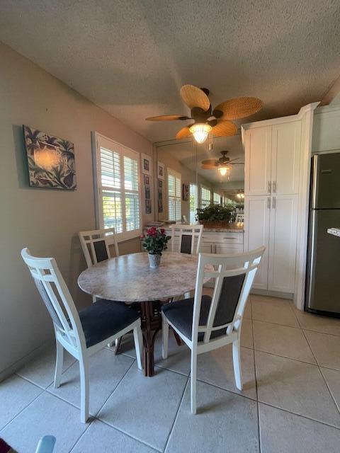 tiled dining area with ceiling fan and a textured ceiling