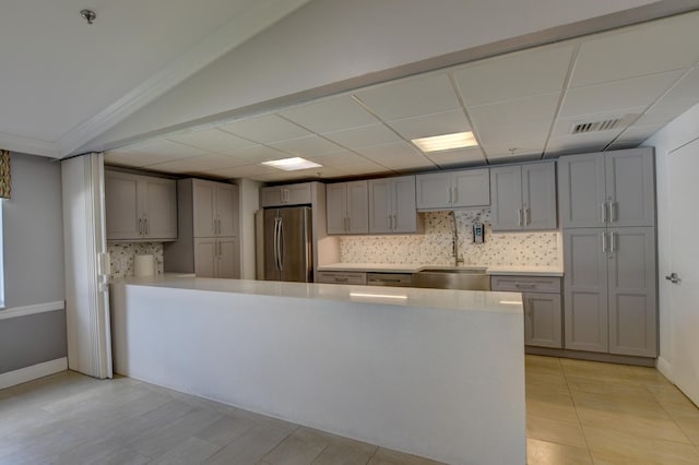 kitchen with gray cabinetry, tasteful backsplash, and stainless steel fridge