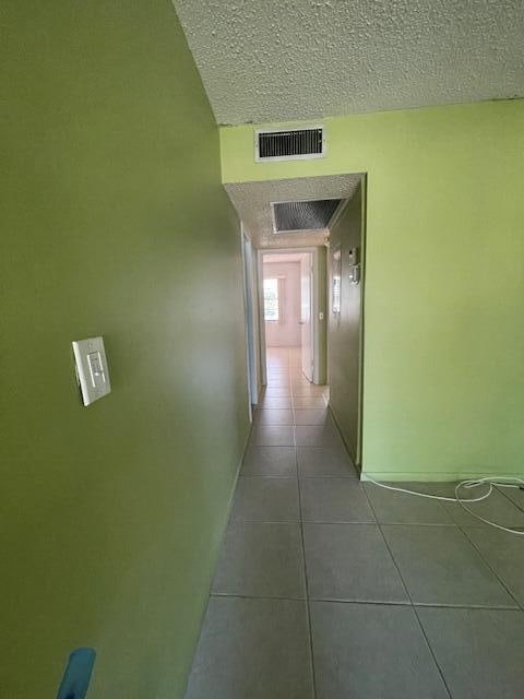 corridor featuring tile patterned flooring and a textured ceiling