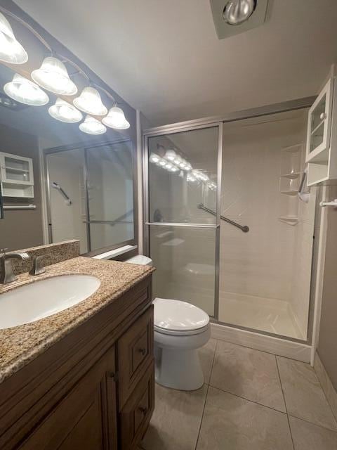 bathroom with vanity, tile patterned flooring, toilet, and an enclosed shower