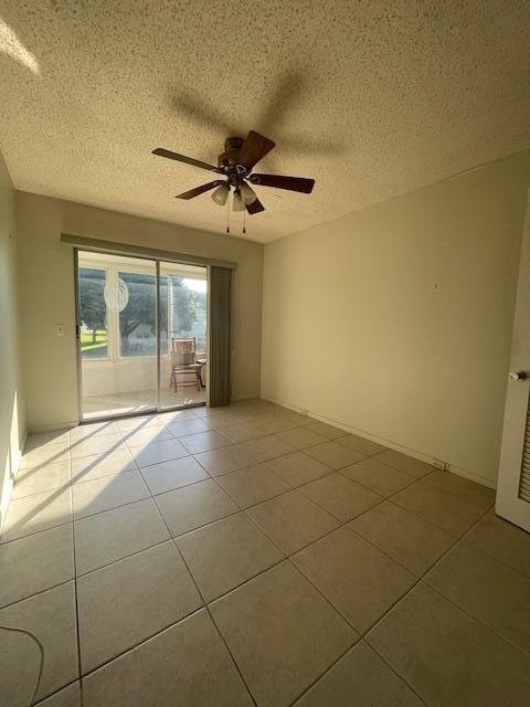 unfurnished room with ceiling fan, a textured ceiling, and light tile patterned flooring