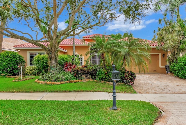 mediterranean / spanish-style house featuring a front yard, an attached garage, and stucco siding