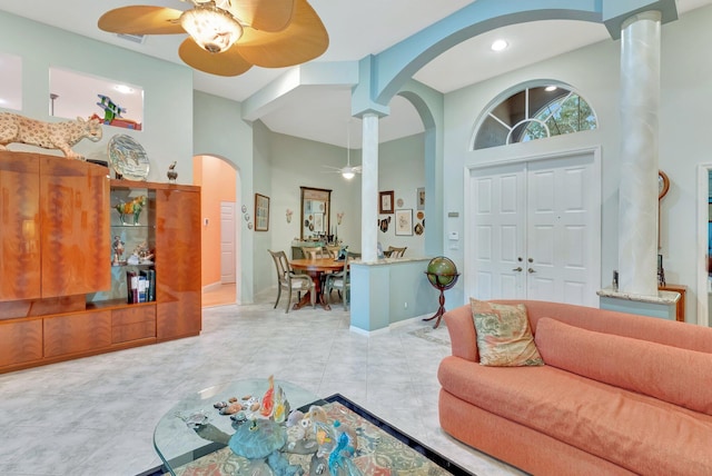 living room featuring a ceiling fan, arched walkways, a towering ceiling, and baseboards