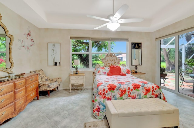 bedroom featuring baseboards, light tile patterned flooring, a raised ceiling, and access to exterior