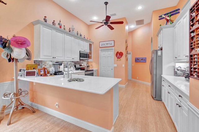 kitchen with visible vents, a breakfast bar area, stainless steel appliances, light countertops, and white cabinetry