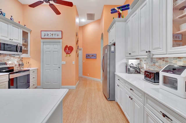 kitchen with light countertops, appliances with stainless steel finishes, glass insert cabinets, and white cabinets