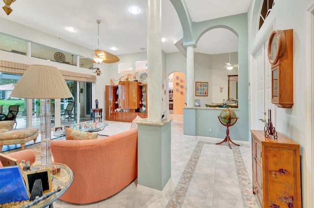 living area featuring arched walkways, recessed lighting, a towering ceiling, a ceiling fan, and baseboards