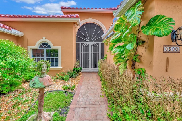 doorway to property featuring a tiled roof and stucco siding