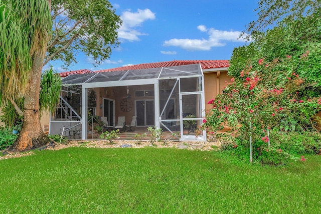 rear view of house with a lanai, a tile roof, and a lawn