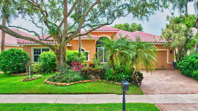 mediterranean / spanish home with a garage, a tile roof, decorative driveway, and stucco siding