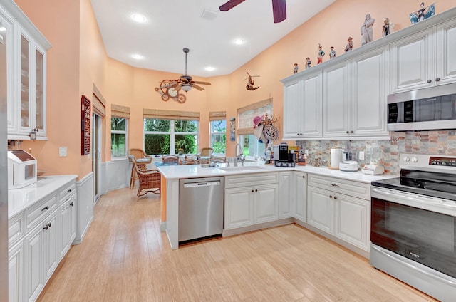 kitchen featuring light countertops, appliances with stainless steel finishes, glass insert cabinets, white cabinets, and a peninsula