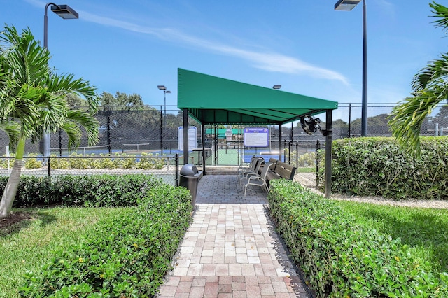 view of community featuring a tennis court, a gate, and fence