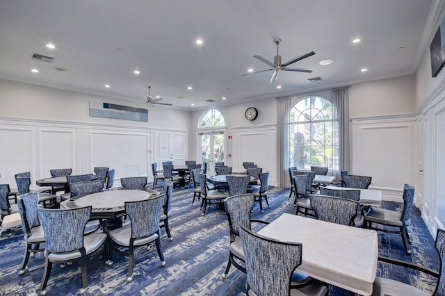 dining area with crown molding, a ceiling fan, visible vents, and a decorative wall