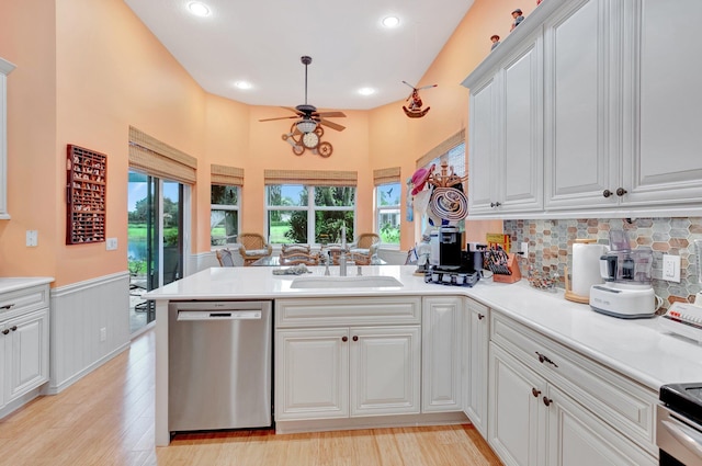 kitchen with stainless steel appliances, a peninsula, a sink, white cabinetry, and light countertops