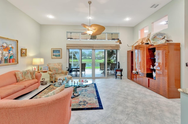 living room featuring a ceiling fan, visible vents, and a towering ceiling