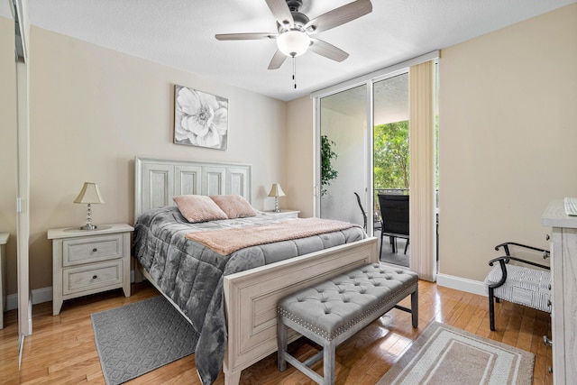 bedroom with baseboards, light wood-style floors, a textured ceiling, and access to exterior