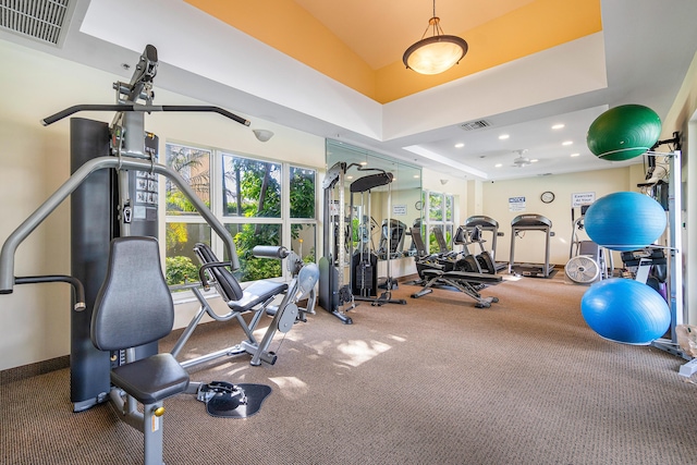 exercise room featuring recessed lighting, a raised ceiling, visible vents, and baseboards