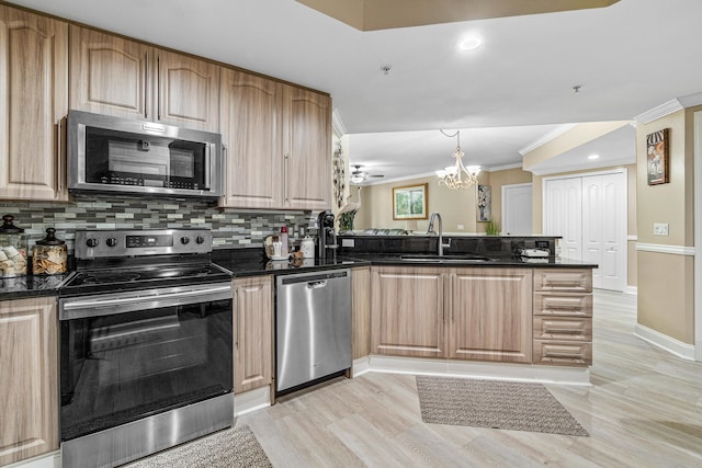 kitchen with ornamental molding, tasteful backsplash, a notable chandelier, kitchen peninsula, and stainless steel appliances