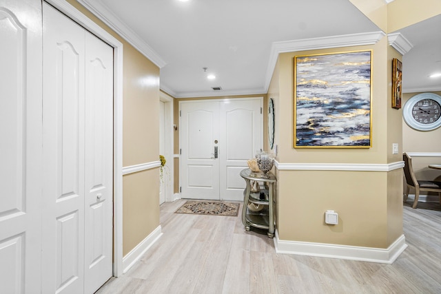 entrance foyer featuring light wood-style flooring, baseboards, and crown molding