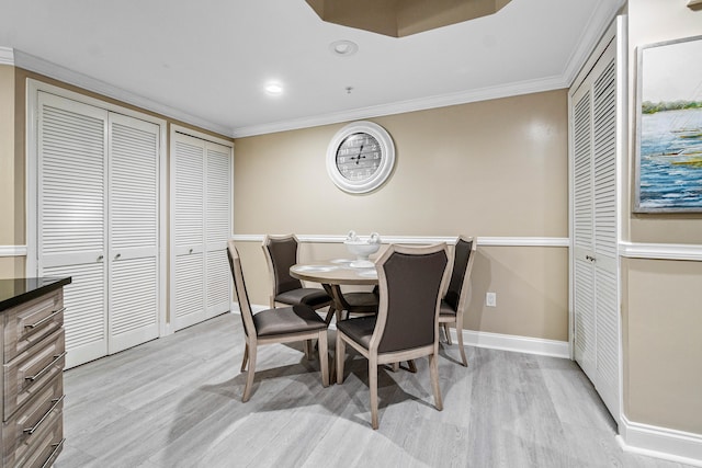 dining area with baseboards, light wood finished floors, and crown molding