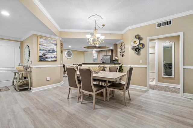 dining area with crown molding, visible vents, a notable chandelier, and light wood finished floors