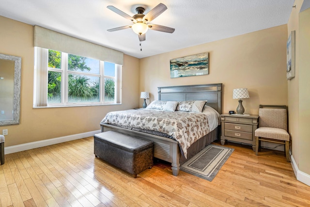 bedroom with a ceiling fan, light wood-type flooring, and baseboards