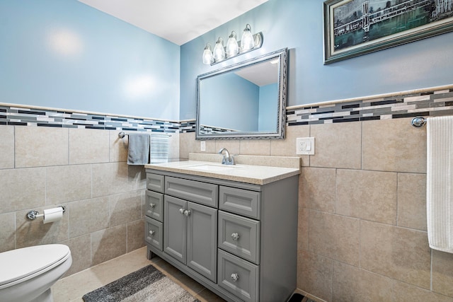 bathroom with tile patterned flooring, vanity, toilet, and tile walls