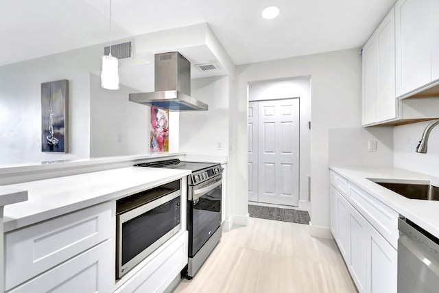 kitchen featuring sink, appliances with stainless steel finishes, white cabinetry, island exhaust hood, and decorative light fixtures