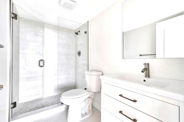 bathroom with a shower with door, vanity, and toilet