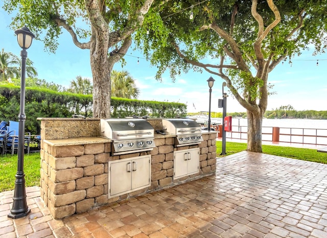 view of patio / terrace featuring a water view, an outdoor kitchen, and area for grilling