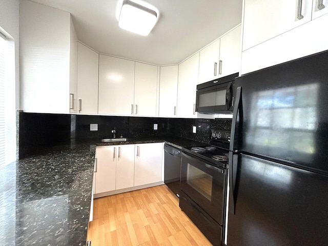 kitchen featuring decorative backsplash, dark stone countertops, black appliances, and light hardwood / wood-style floors