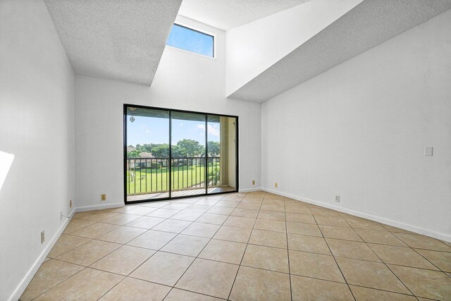 tiled spare room with high vaulted ceiling, a textured ceiling, and a healthy amount of sunlight