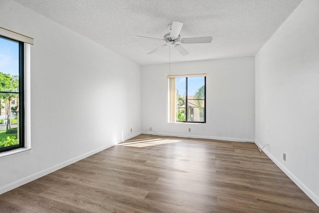 unfurnished room featuring a textured ceiling, baseboards, and wood finished floors