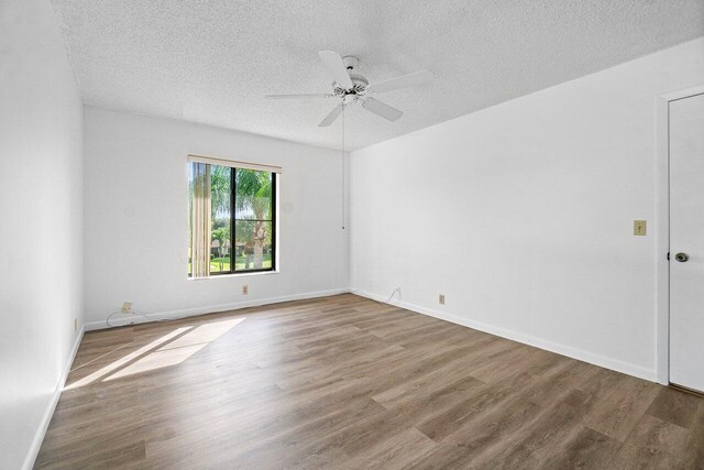 empty room featuring ceiling fan, wood-type flooring, and a textured ceiling