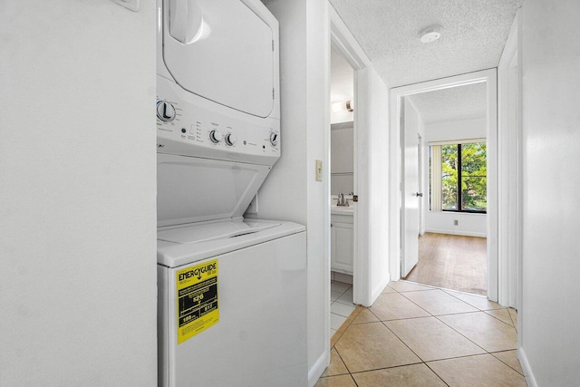 laundry room with sink, a textured ceiling, stacked washer and clothes dryer, and light hardwood / wood-style floors