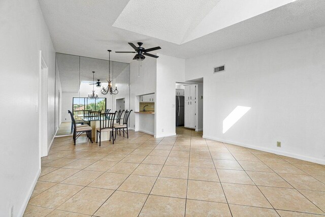 interior space featuring ceiling fan with notable chandelier, a textured ceiling, light tile patterned flooring, and high vaulted ceiling