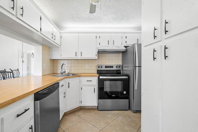 kitchen with stainless steel appliances, white cabinetry, light tile patterned flooring, tasteful backsplash, and sink