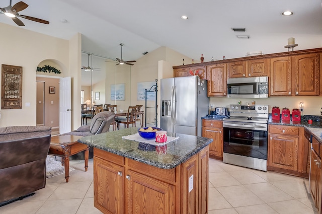 kitchen featuring ceiling fan, appliances with stainless steel finishes, light tile patterned flooring, high vaulted ceiling, and a kitchen island