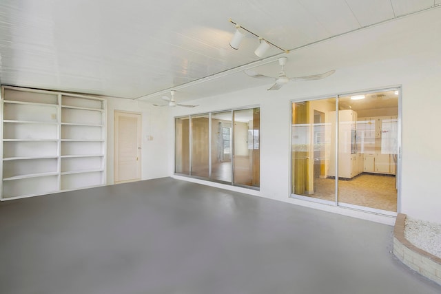 spare room featuring concrete floors, built in features, and ceiling fan