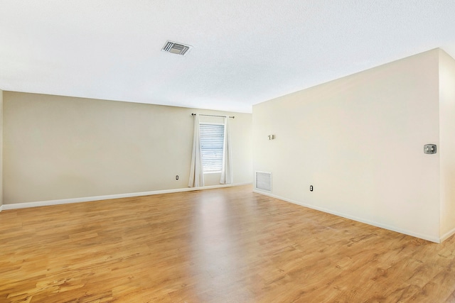 spare room featuring light hardwood / wood-style floors and a textured ceiling