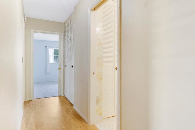 hall with a textured ceiling and light hardwood / wood-style floors