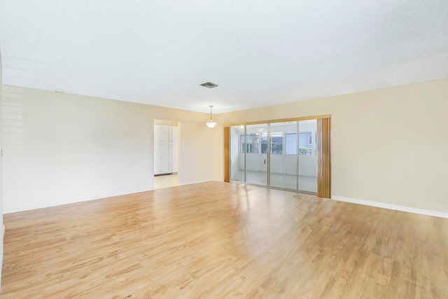 empty room featuring light wood-type flooring and a textured ceiling